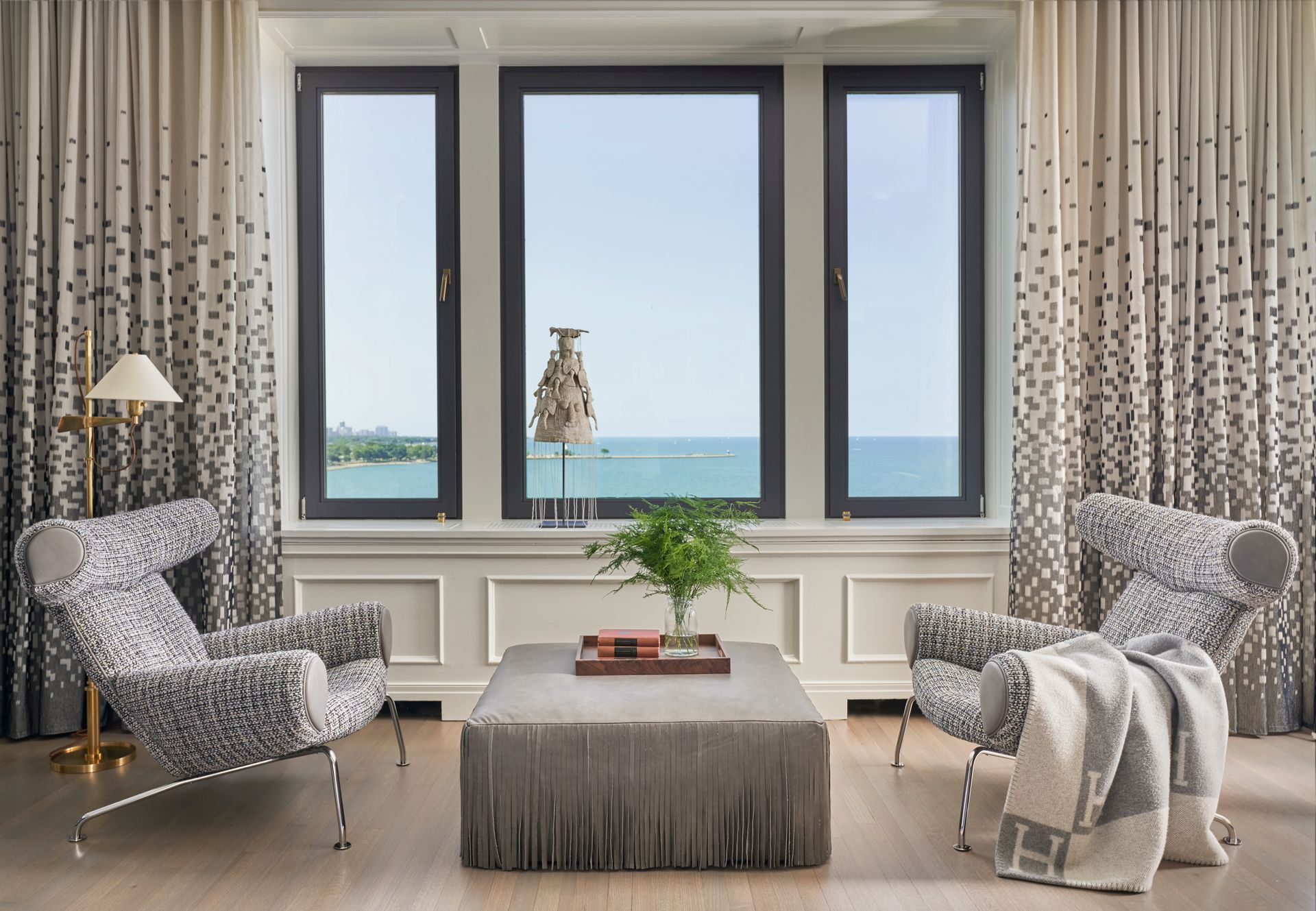 A living room with two chairs and a coffee table with a view of the ocean.