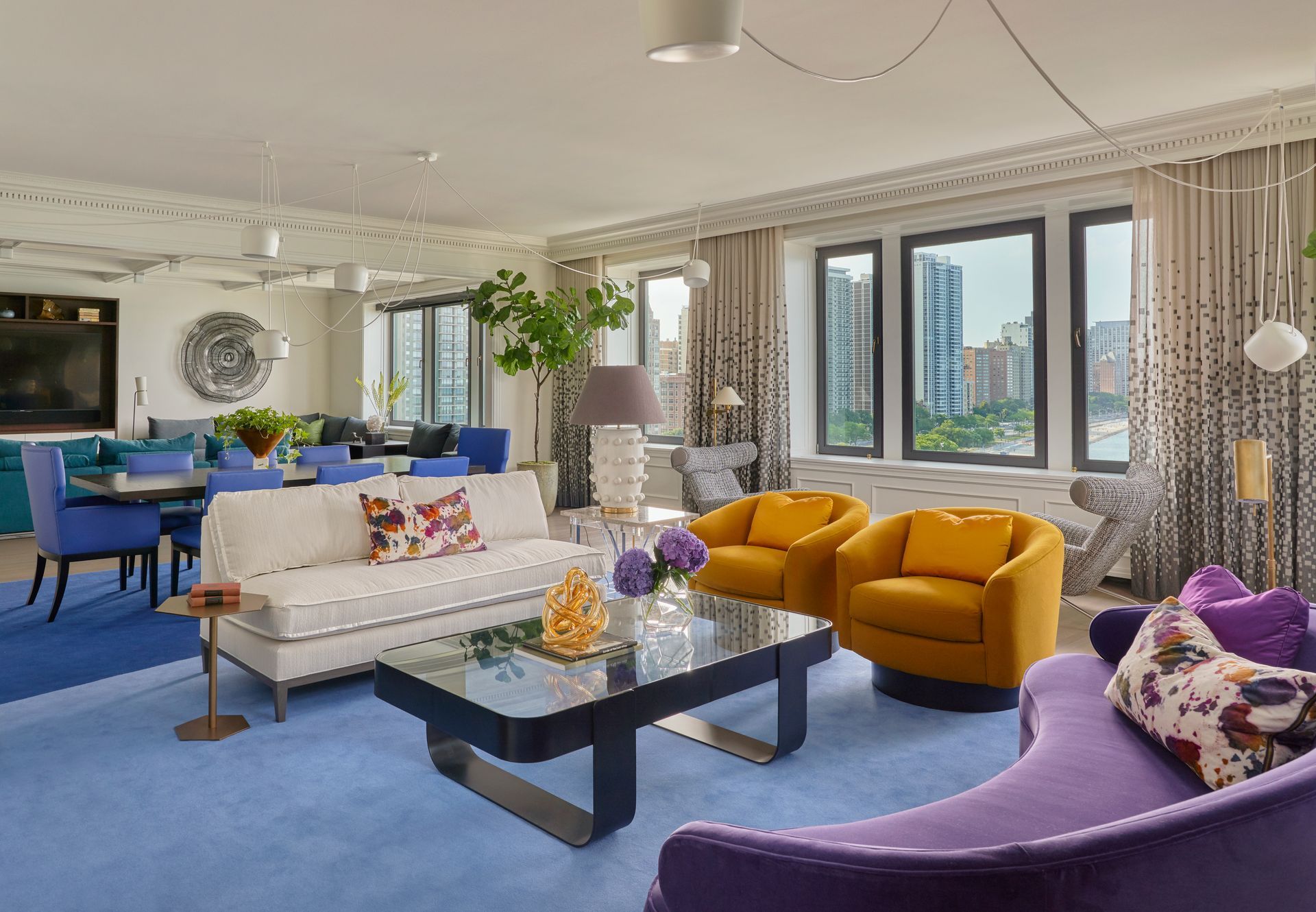 A living room with a purple couch, yellow chairs, and a coffee table.