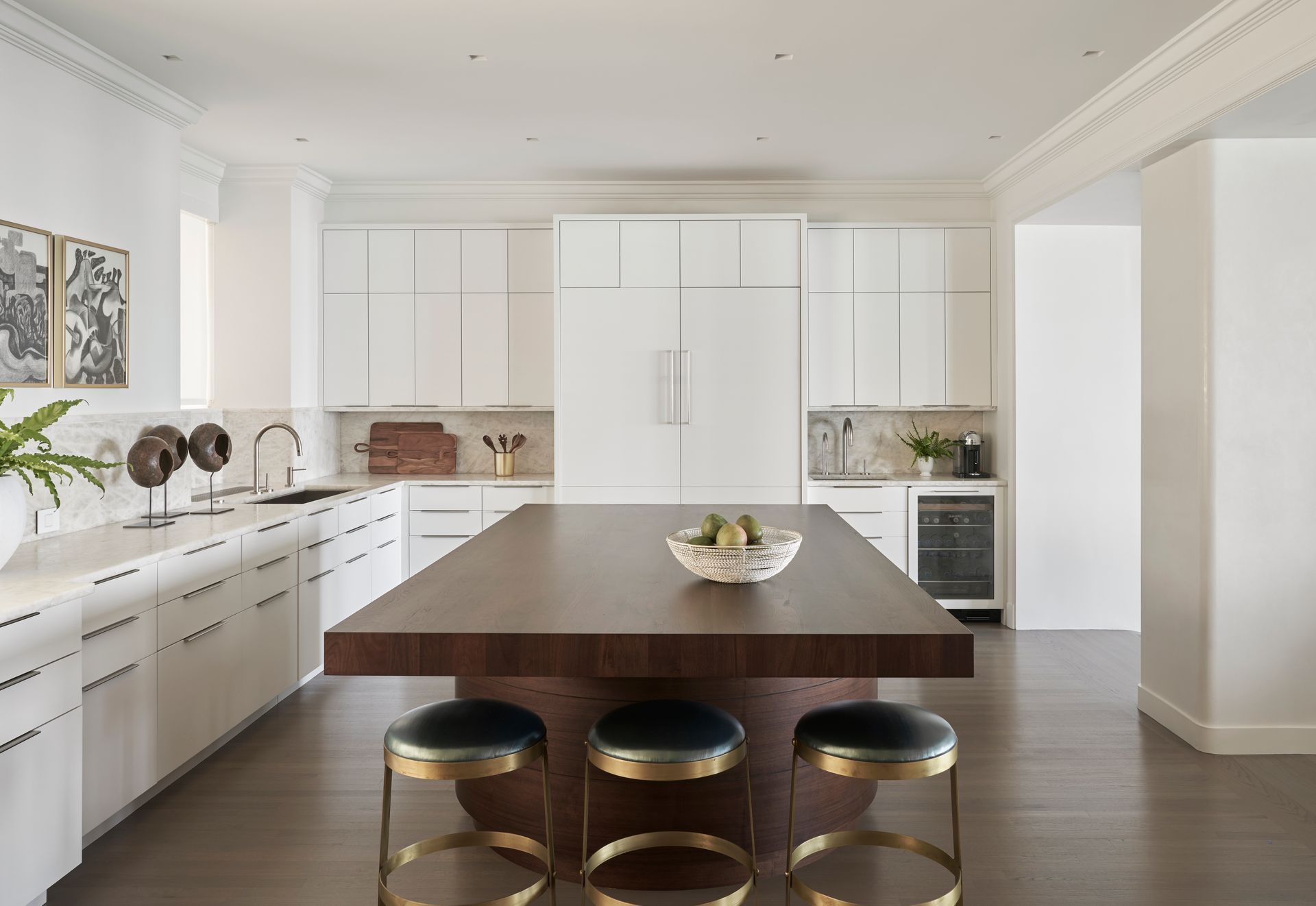 A kitchen with a large wooden table and stools