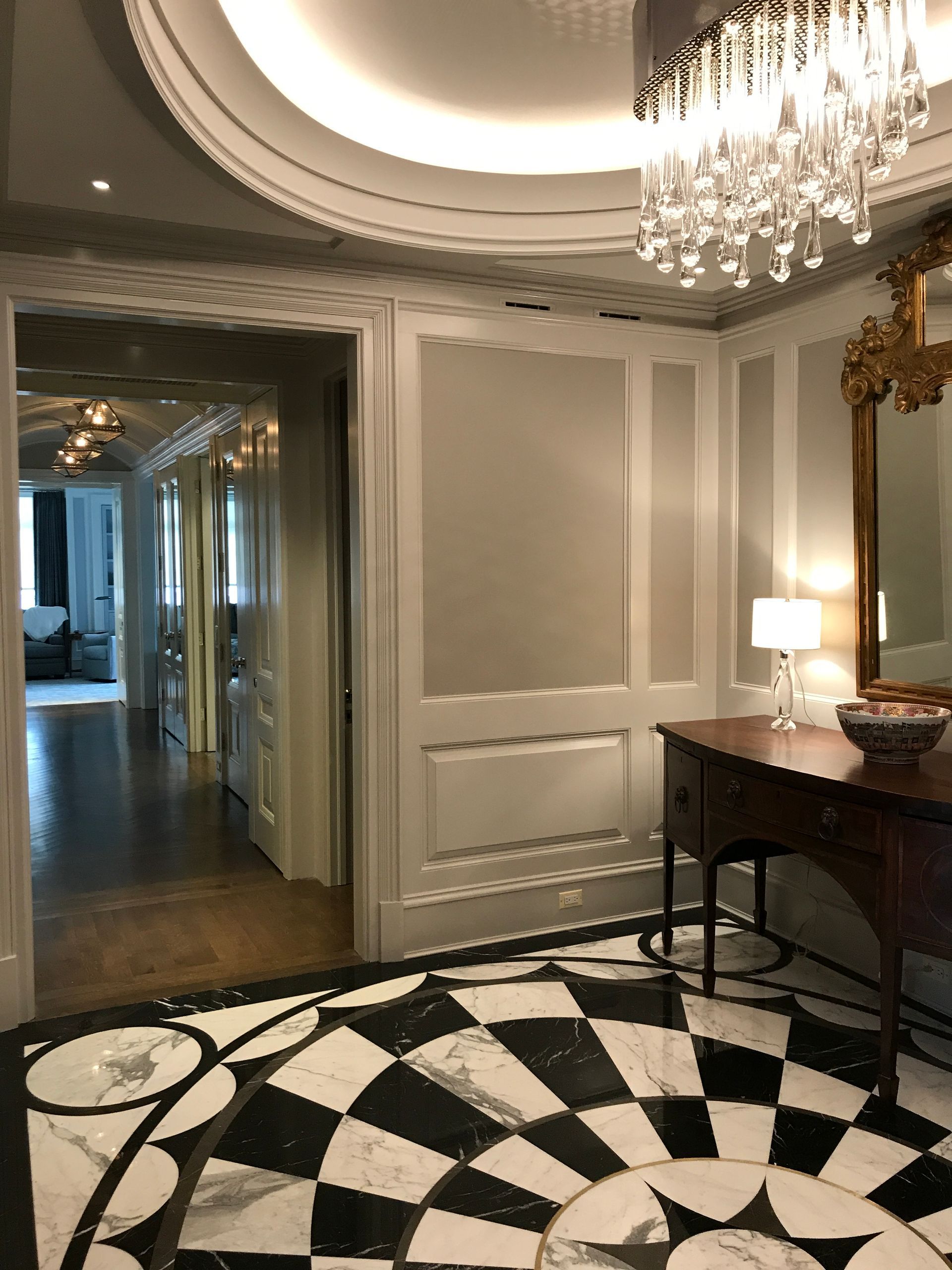 A hallway with a checkered floor and a chandelier.