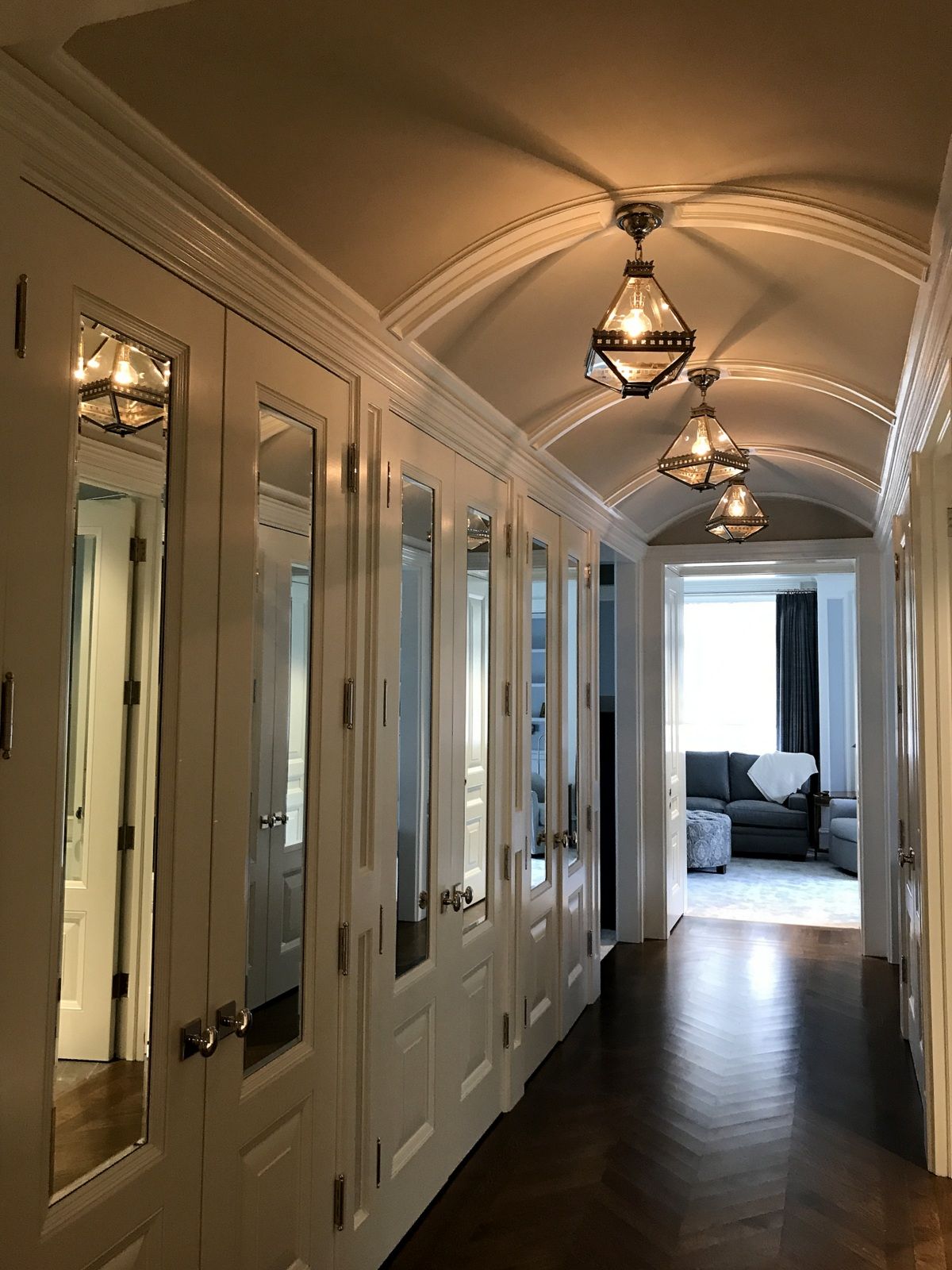 A long hallway with mirrored doors and a couch in the background