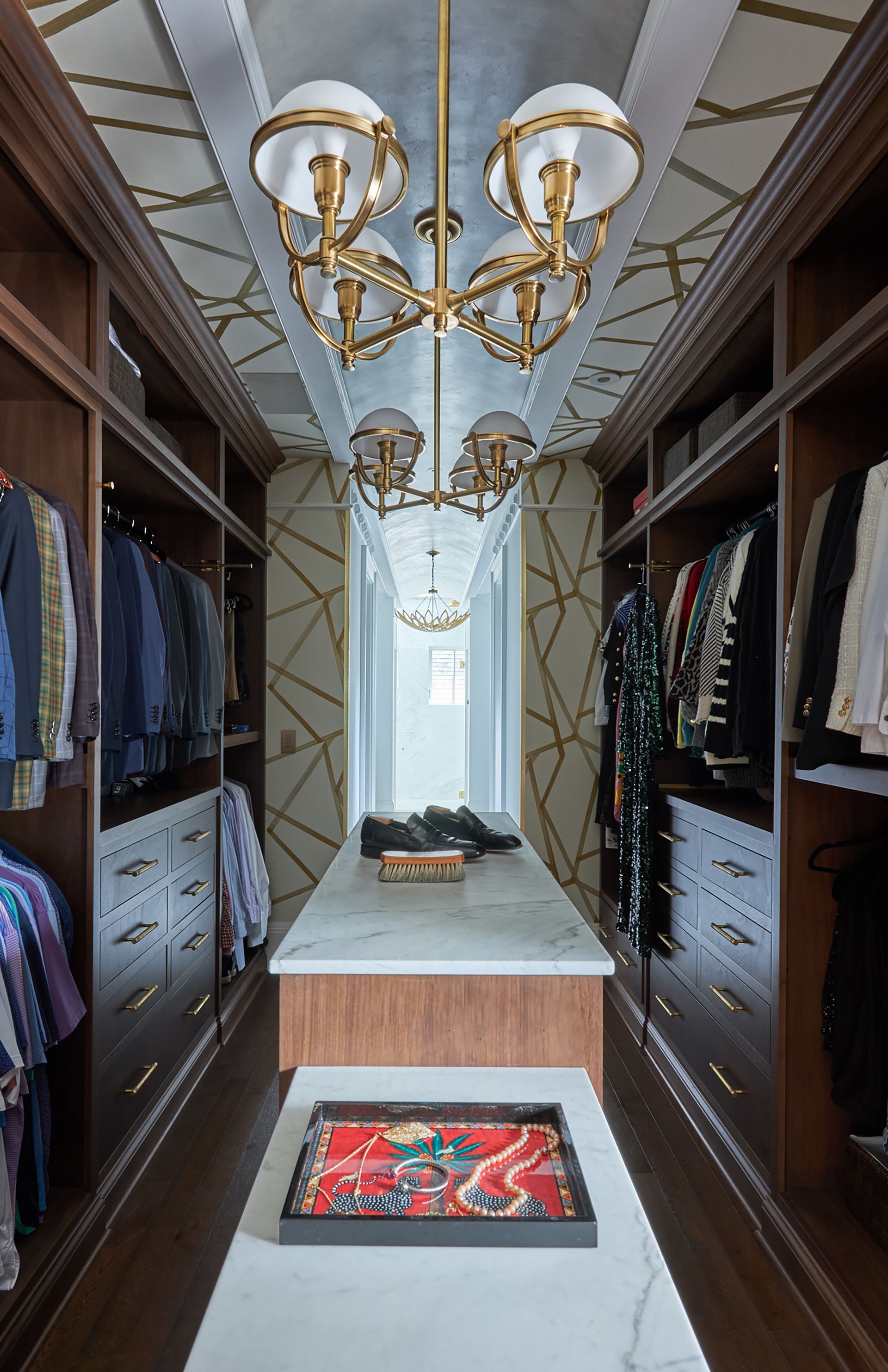 A walk in closet filled with lots of clothes and a chandelier.