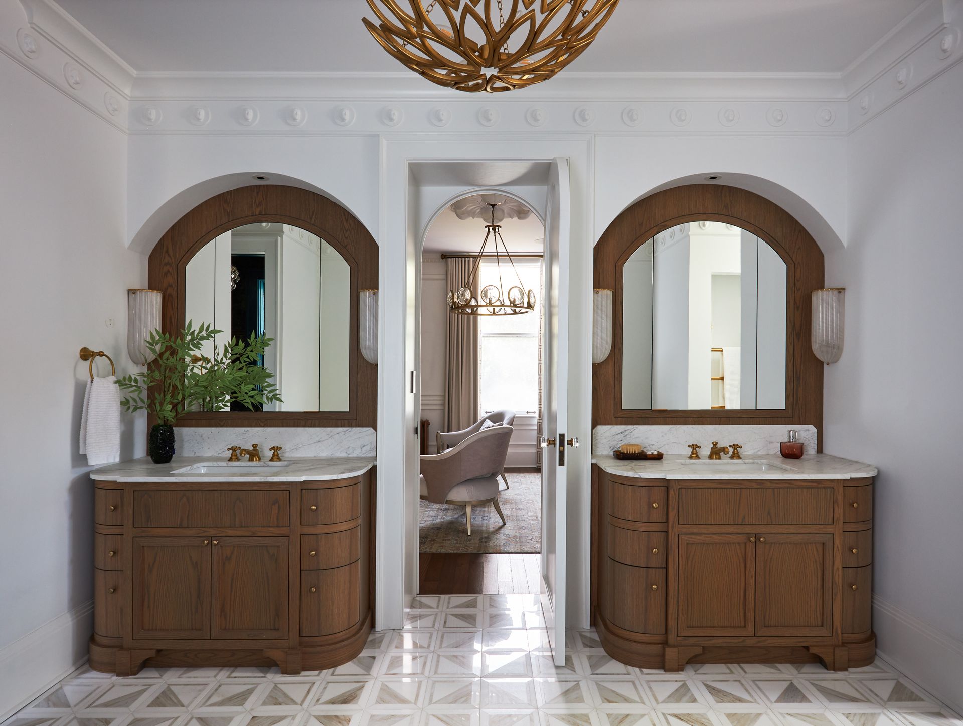 A bathroom with two sinks, two mirrors, and a chandelier.
