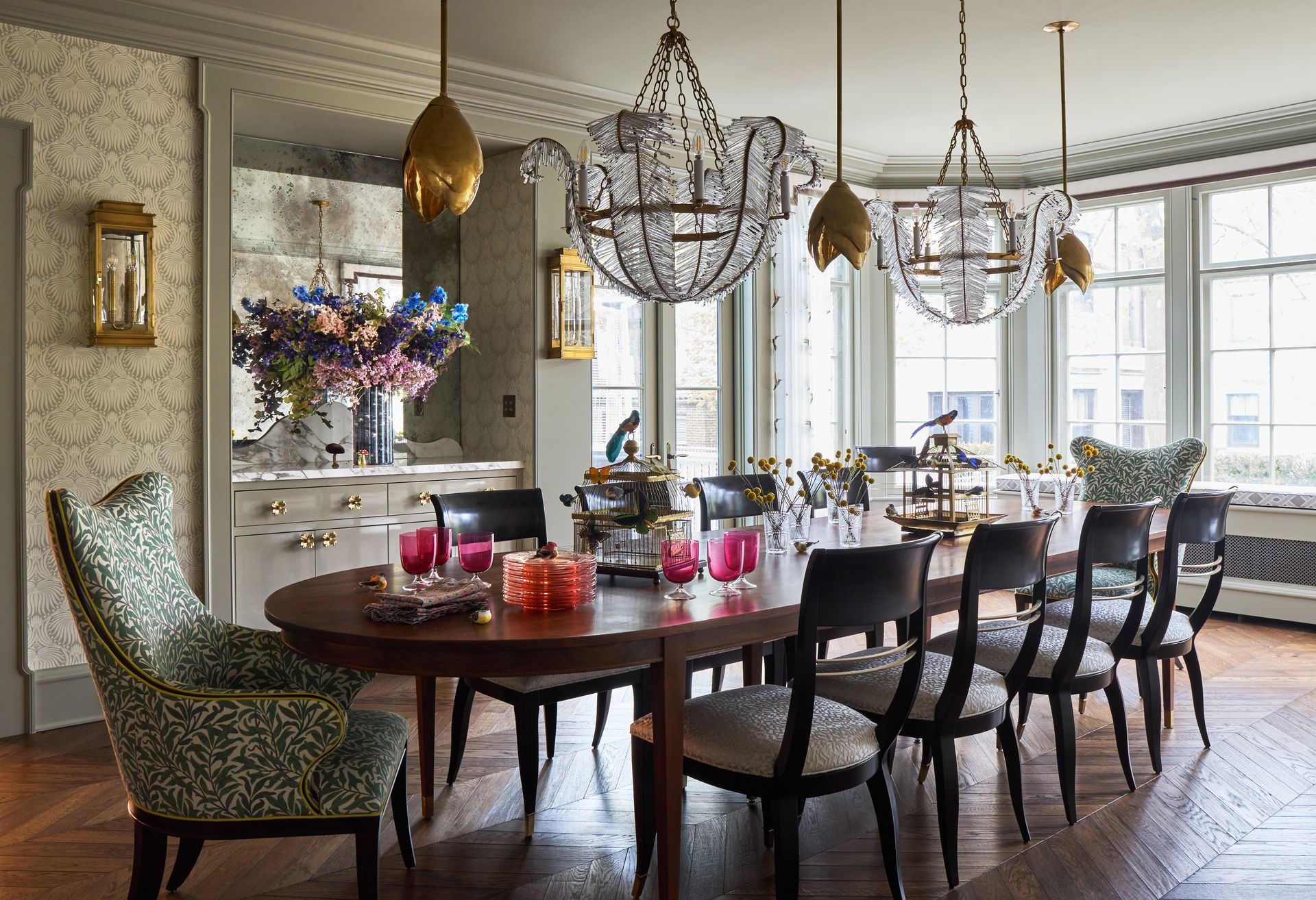 A dining room with a table and chairs and chandeliers hanging from the ceiling.