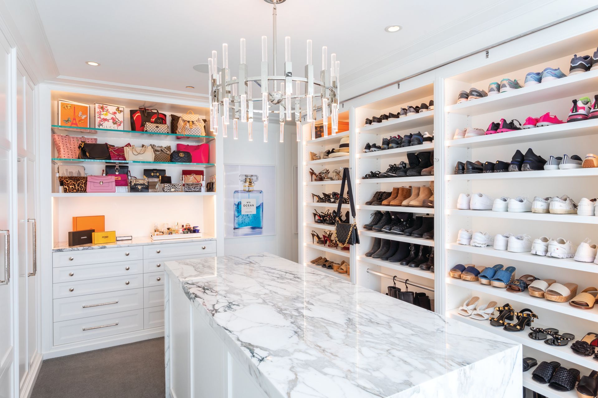 A beautiful walk-in closet filled with lots of shoes and handbags.