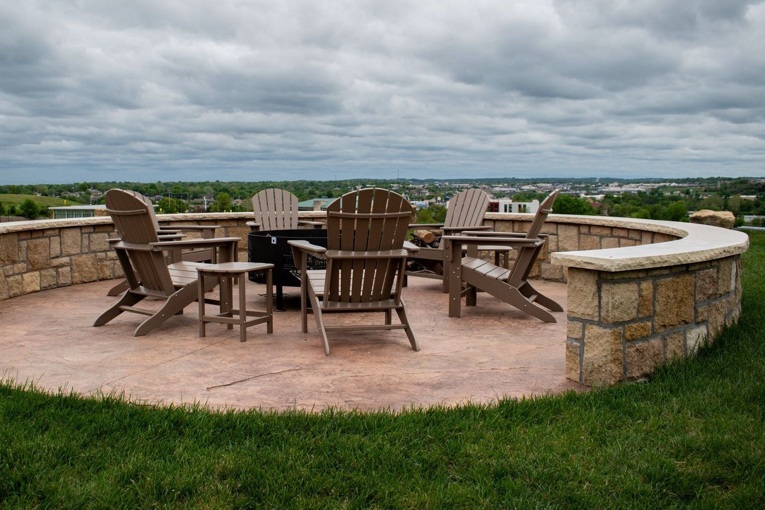 A group of chairs are sitting around a fire pit on a patio.