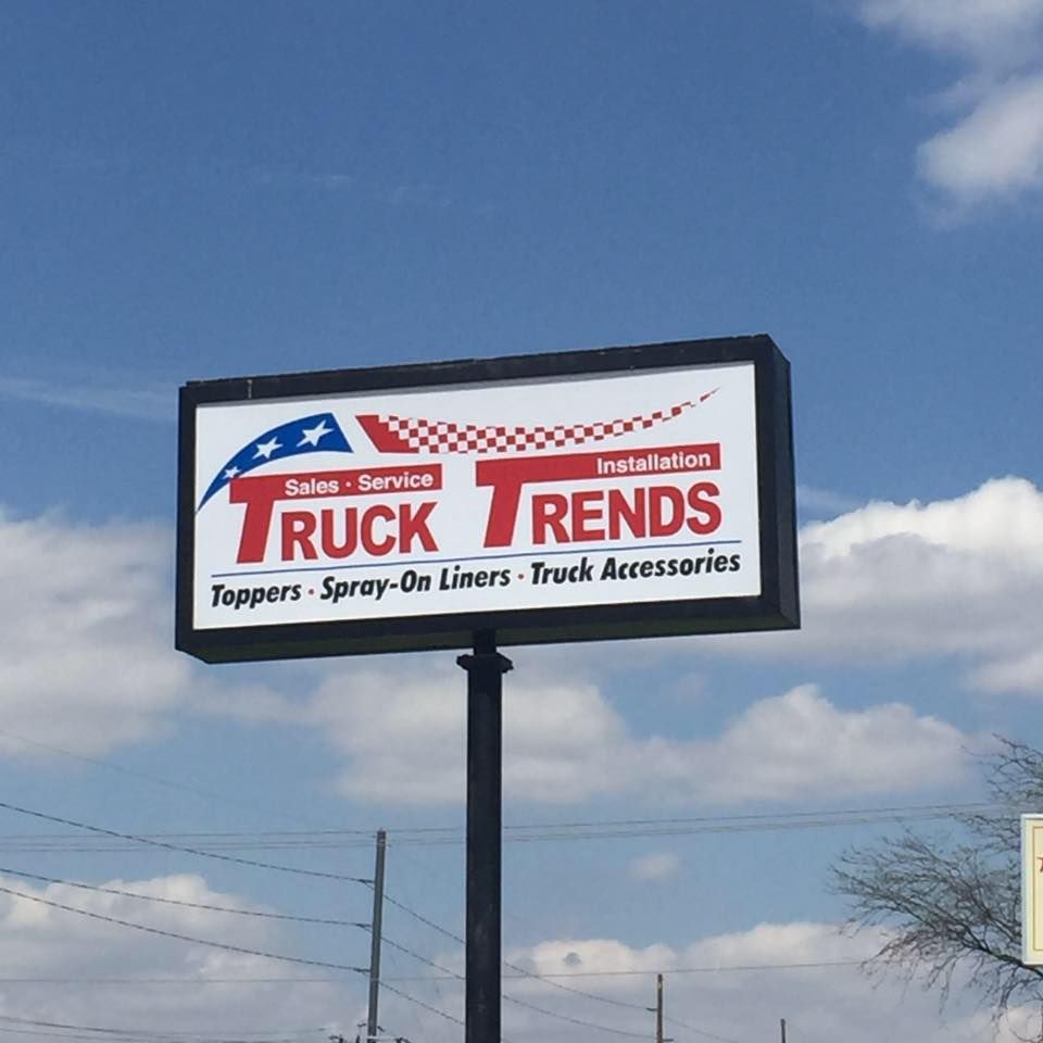 Sign for Truck Trends; red and blue logo, offers sales, service, toppers, spray-on liners, and truck accessories.