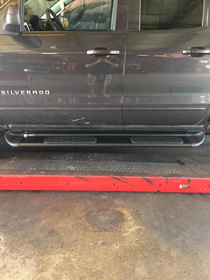 Dark gray Silverado truck with black running boards, parked in a garage.