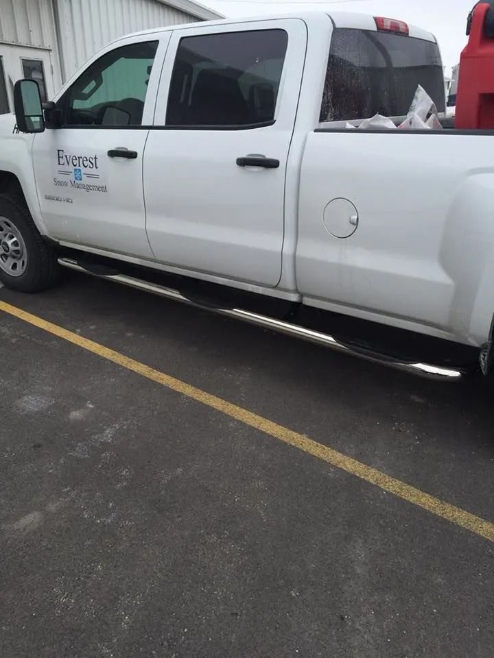 White pickup truck with company logo parked next to yellow line. Chrome running boards.
