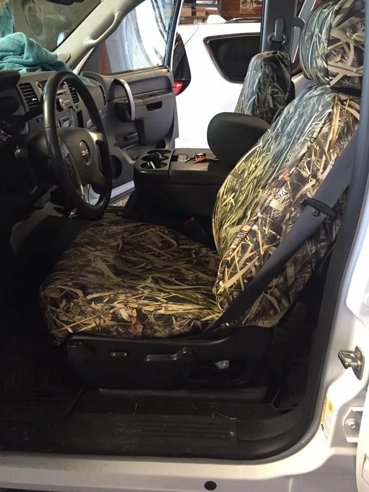 Truck interior with camouflage seat cover. Steering wheel, console, and open door visible.