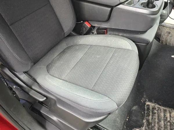 Gray upholstered driver's seat inside a vehicle. Seatbelt is visible. Black and gray console nearby.