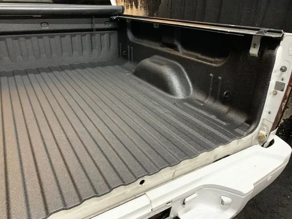 White pickup truck bed with textured black bedliner.