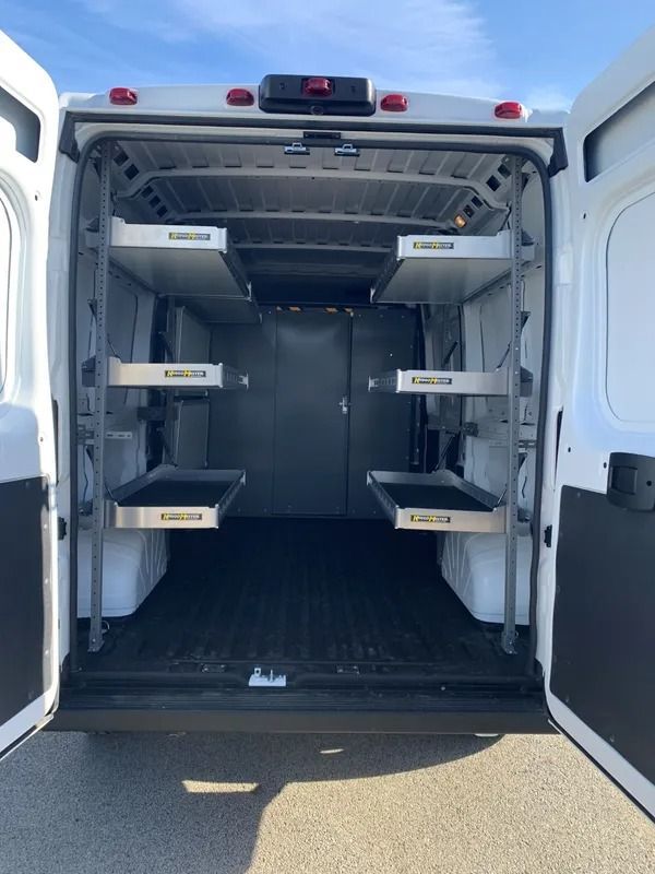 Interior of a white van with shelves for transporting bodies; doors are open.