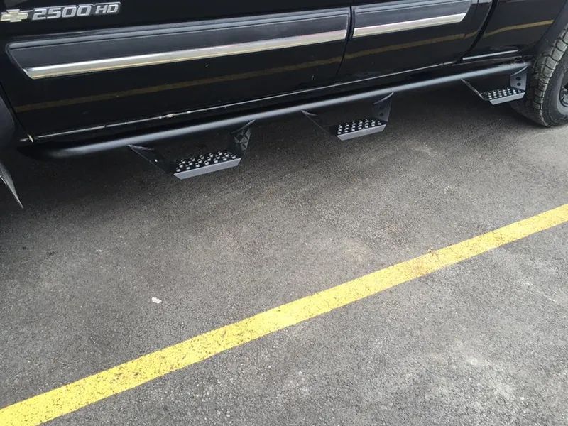 Black truck with running boards; parked on asphalt with yellow line.