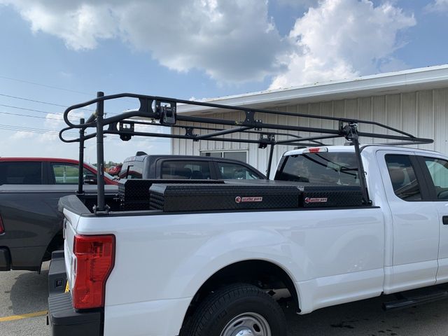 White pickup truck with black truck rack and toolboxes.