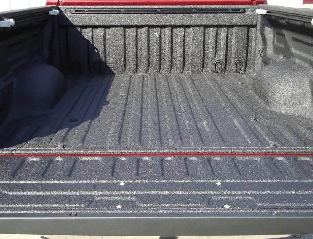 Truck bed interior with a textured black coating and ridged floor.