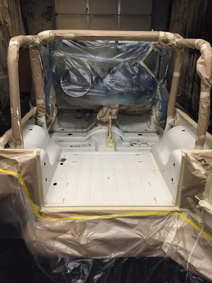White Jeep interior, masked for painting, roll bar, and floorboards, inside a garage.