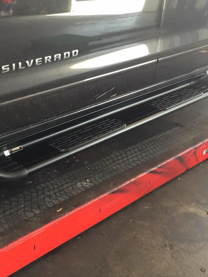 Black Silverado truck with side steps on a red platform.