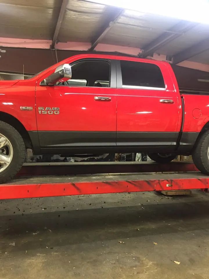 Red Ram 1500 truck on a red lift inside a garage. The truck has black trim and tinted windows.