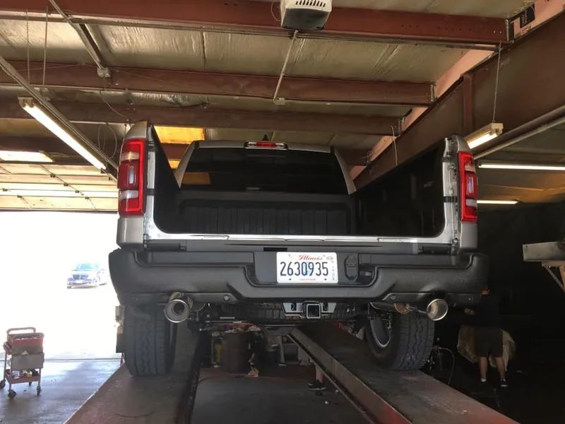 A silver pickup truck on a lift inside a garage. The license plate reads 263035.