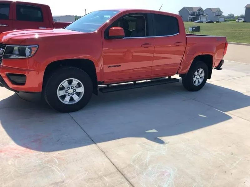 Red Chevrolet Colorado truck parked on a concrete driveway.
