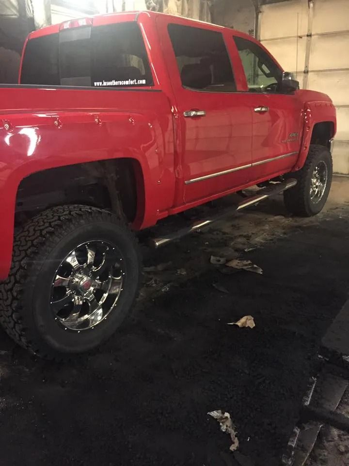 Red pickup truck parked indoors, chrome wheels and running boards.