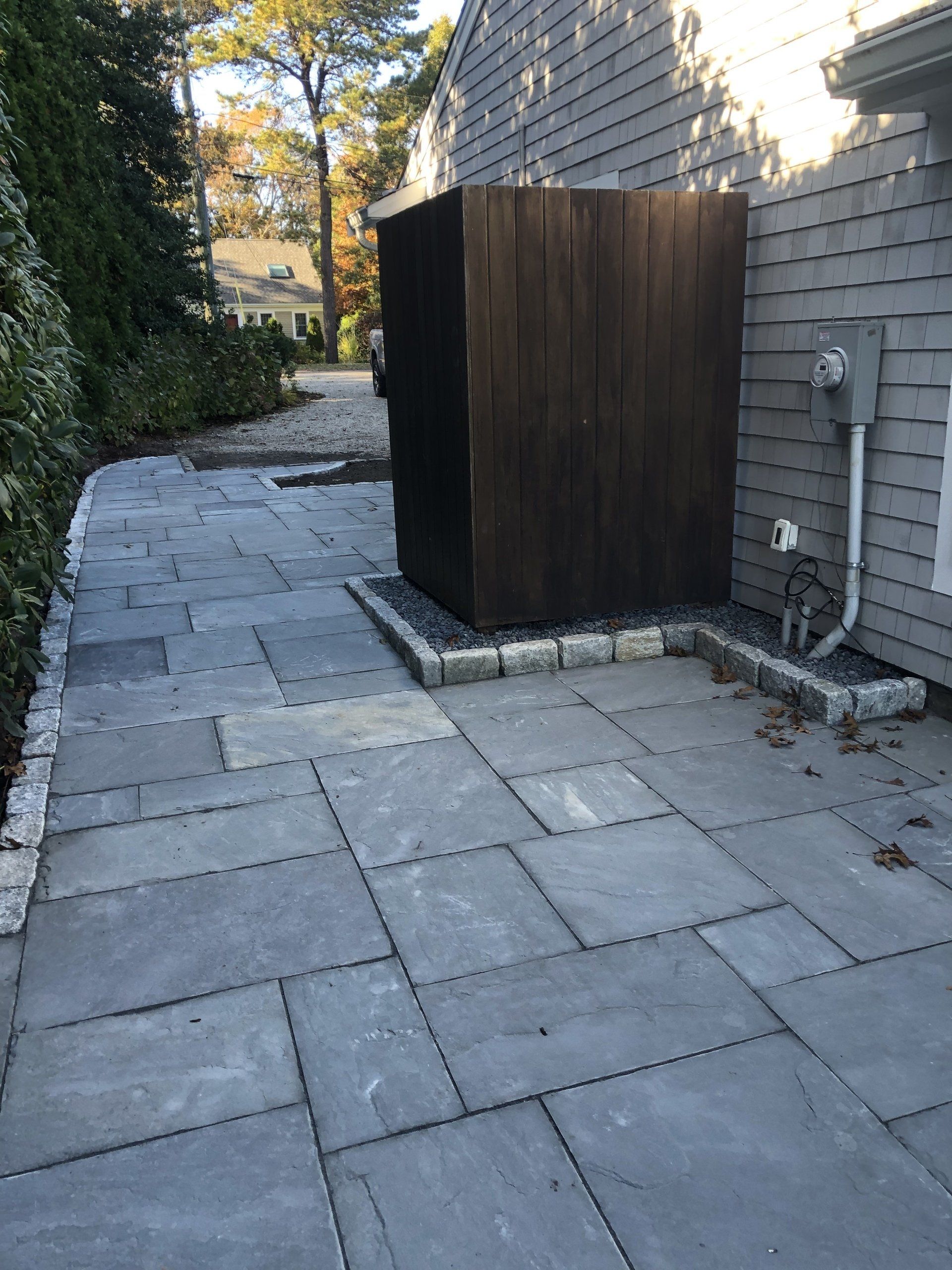 A patio with a wooden shed on the side of a house