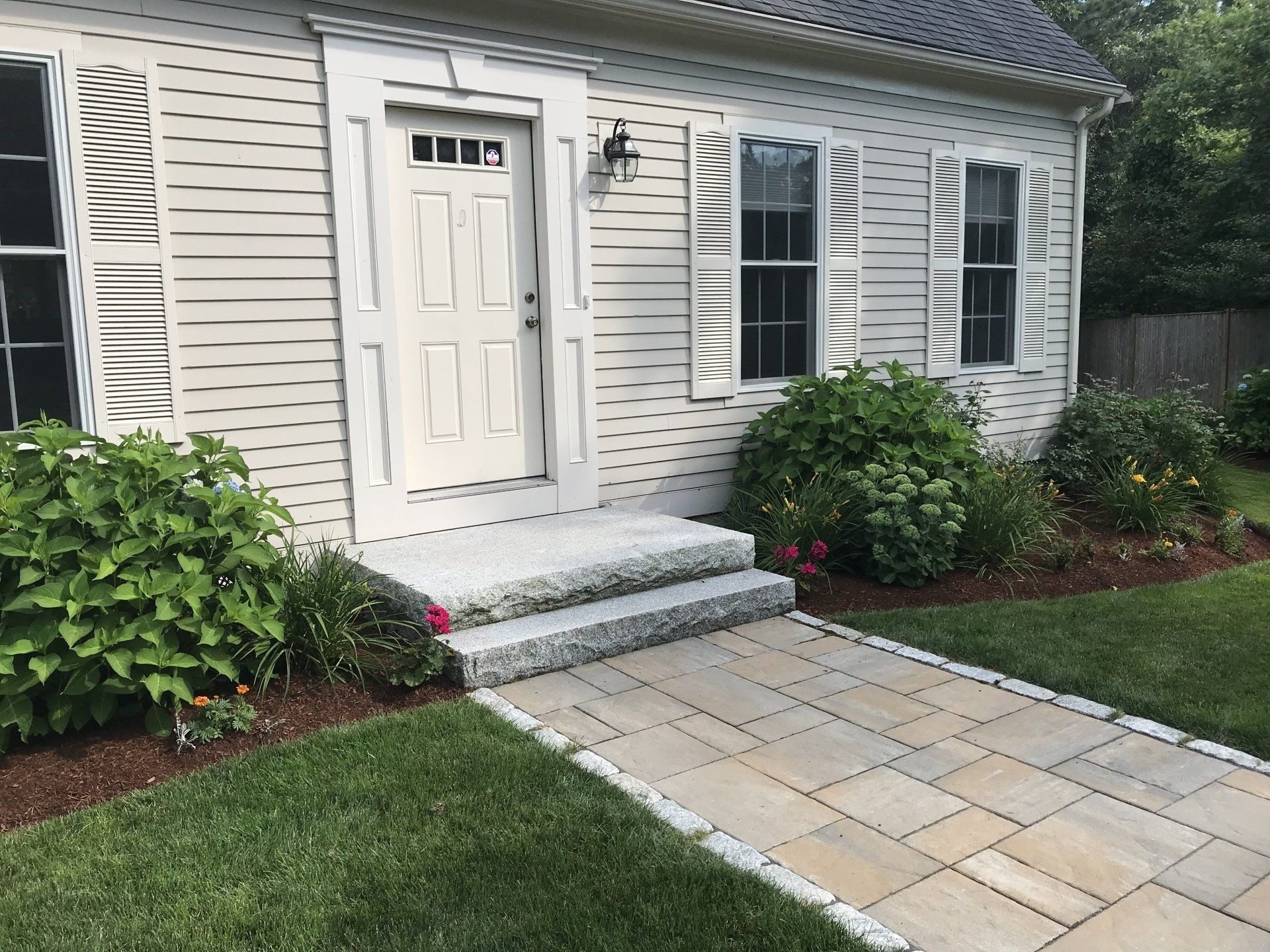 A white house with a stone walkway leading to the front door