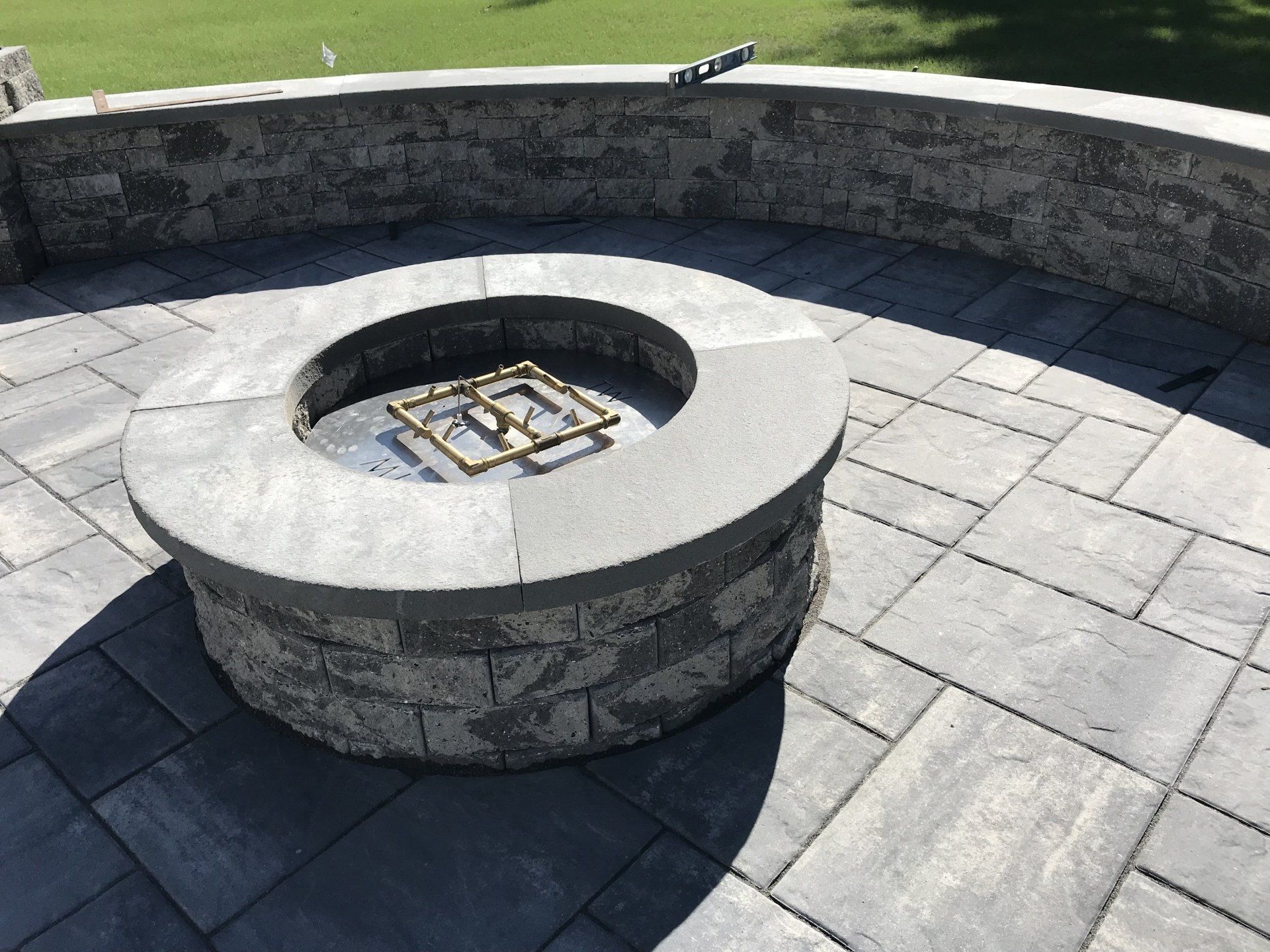 A fire pit is sitting on a patio next to a stone wall
