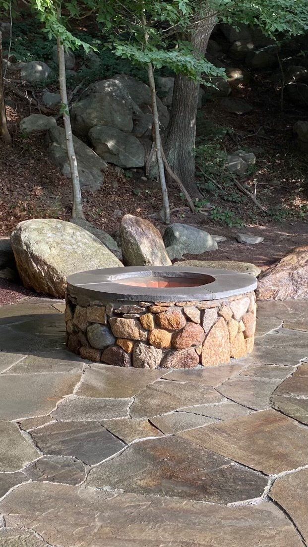 A stone fire pit is sitting on top of a stone patio