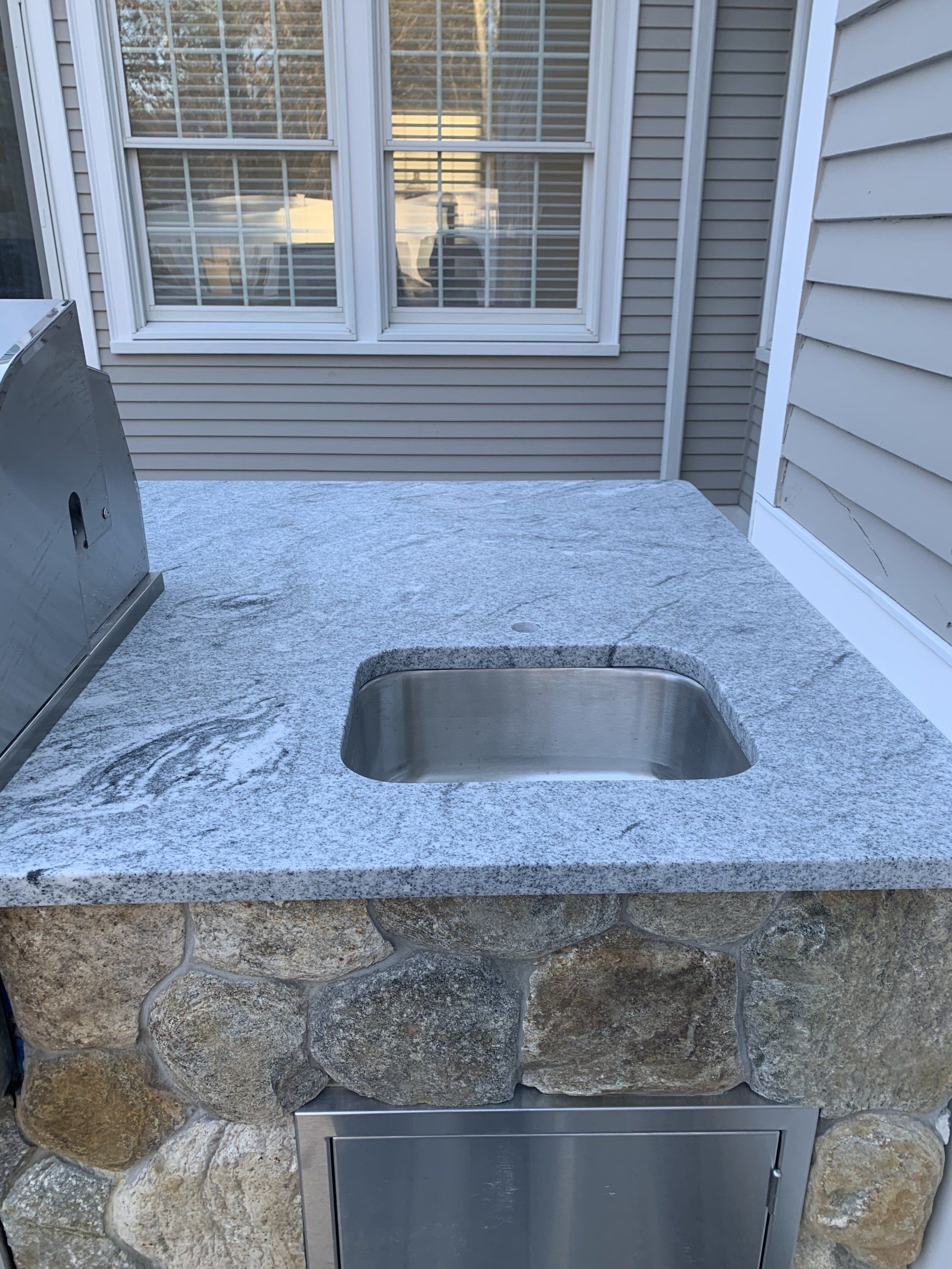 A stainless steel sink is sitting on top of a granite counter next to a window
