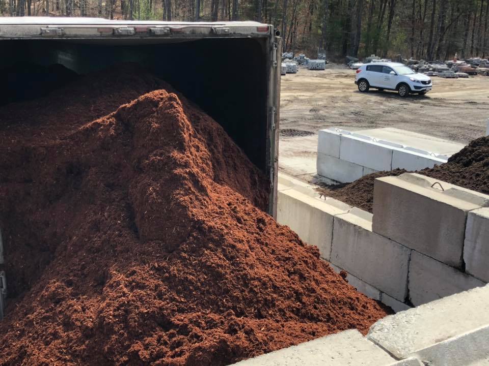 A pile of mulch is being loaded into a truck.