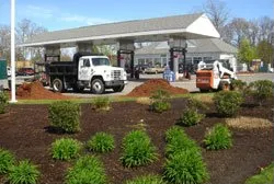A dump truck is parked in front of a gas station