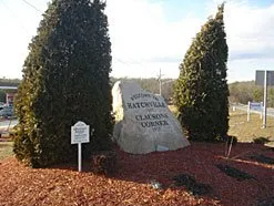 A large rock in the middle of a field with trees in the background