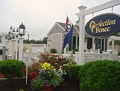 There is a sign that says perfection fence in front of a house.