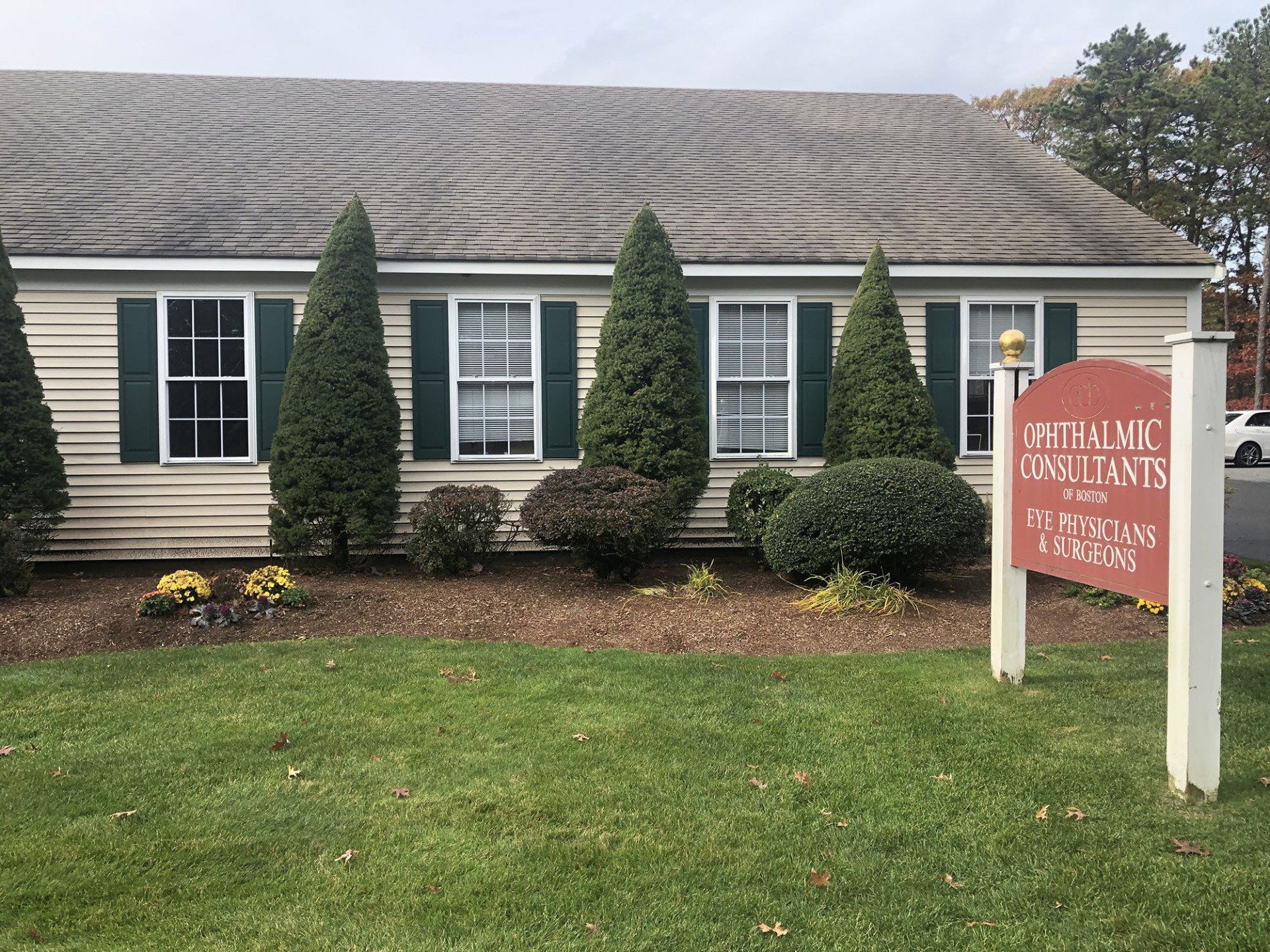 A house with green shutters and a sign in front of it