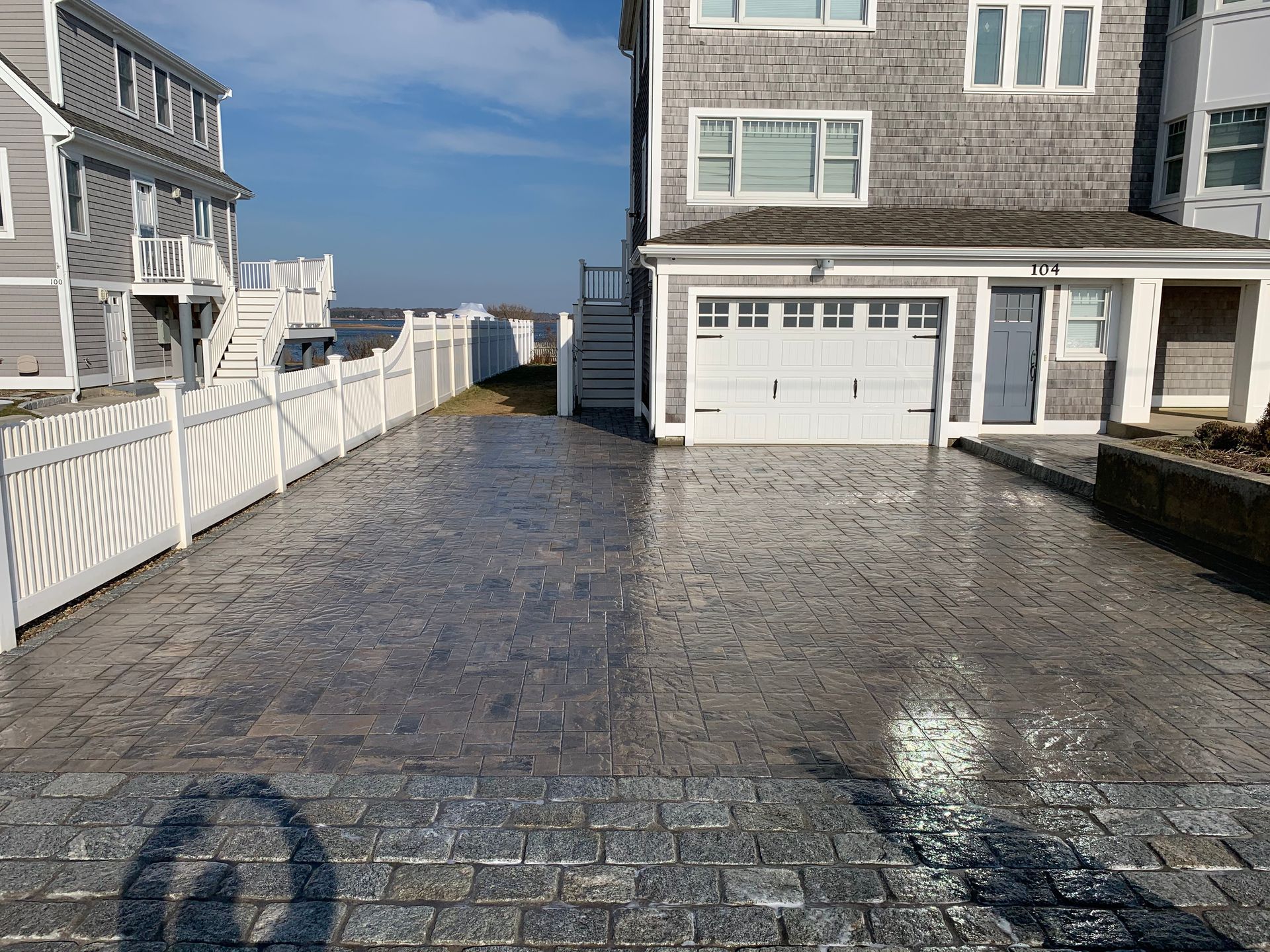 A driveway leads to a house with a white fence.