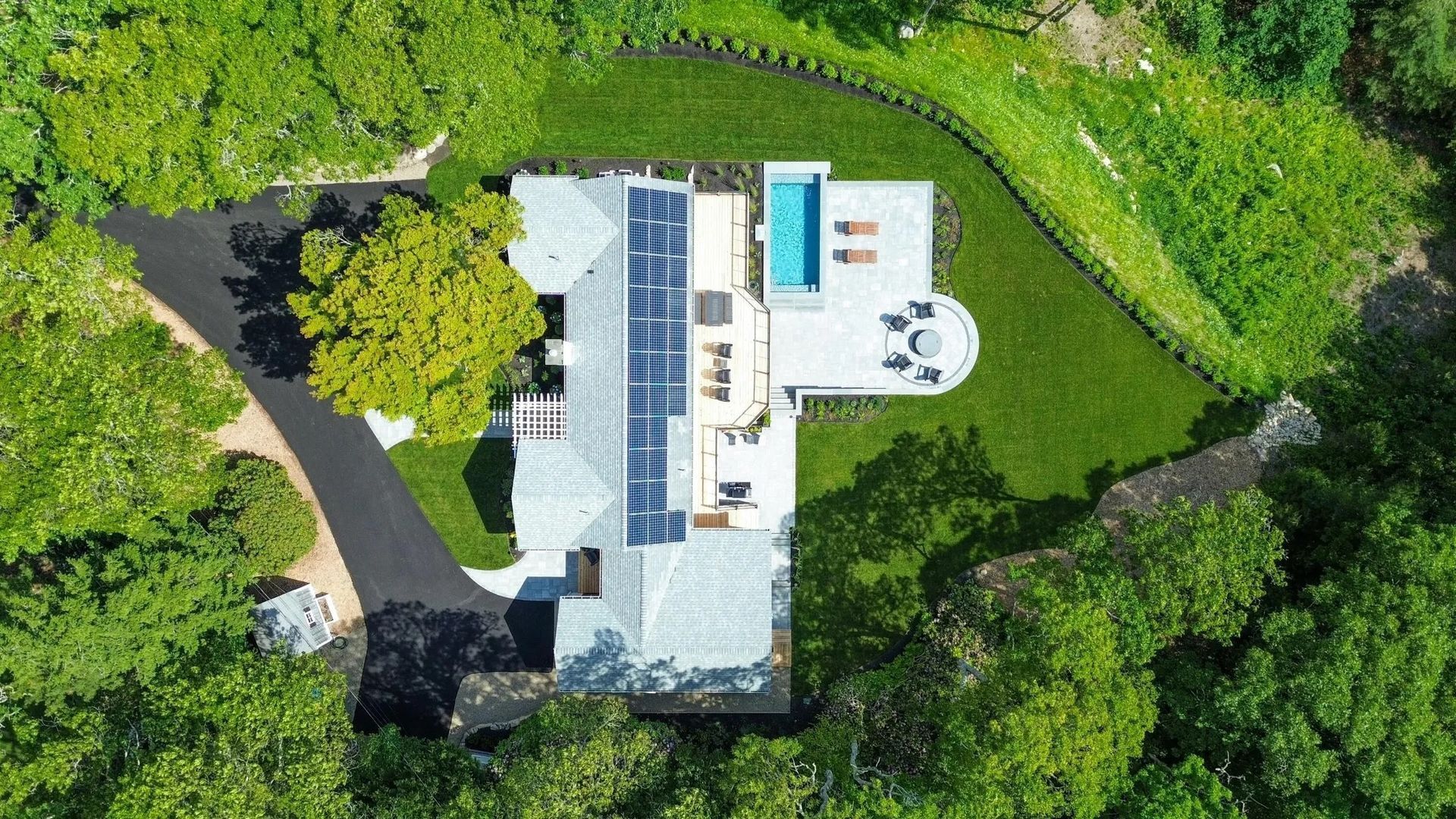 An aerial view of a house surrounded by trees and grass.