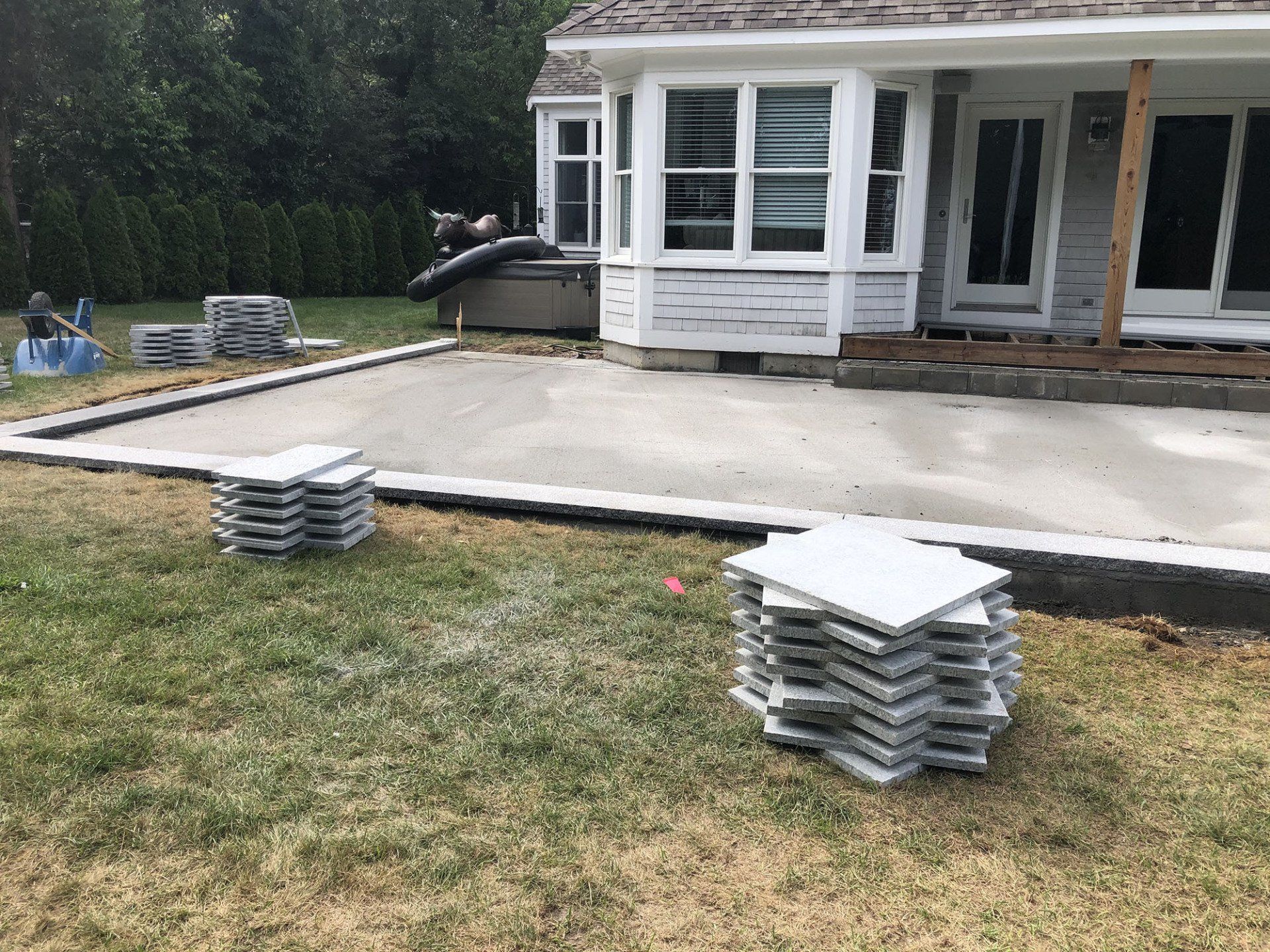 A stack of tiles is sitting in the grass in front of a house.