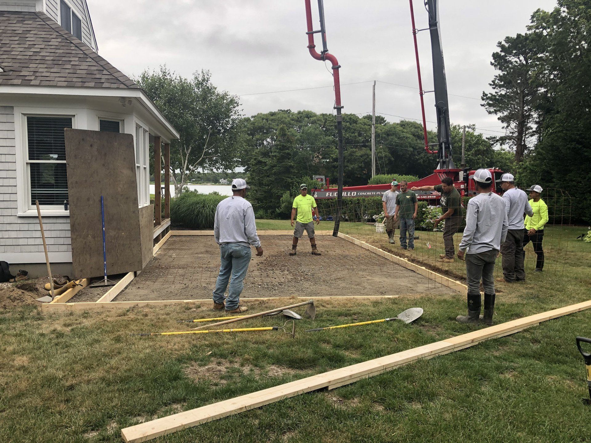 A group of construction workers are working on a patio in front of a house.