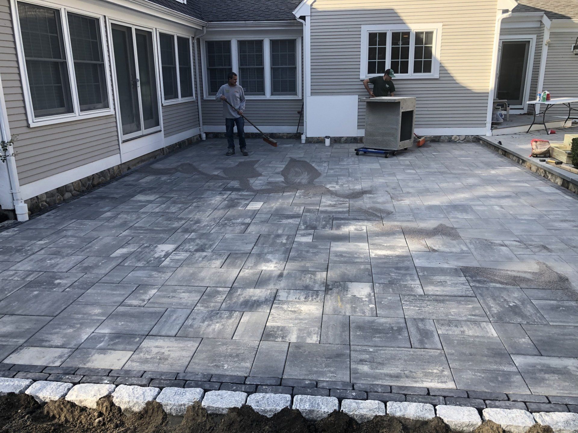 A man is sweeping a patio in front of a house.