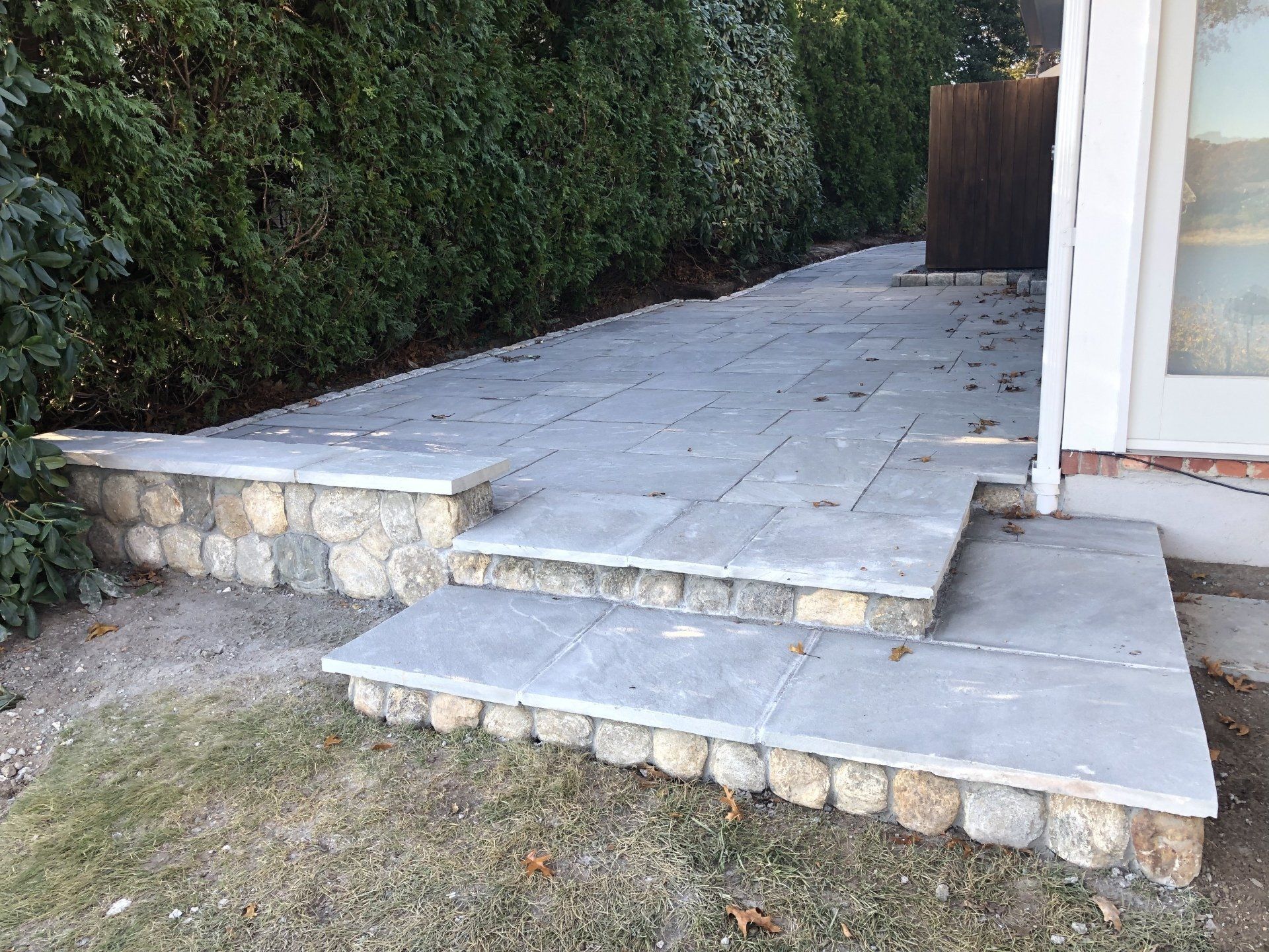 A stone patio with steps leading up to a house.