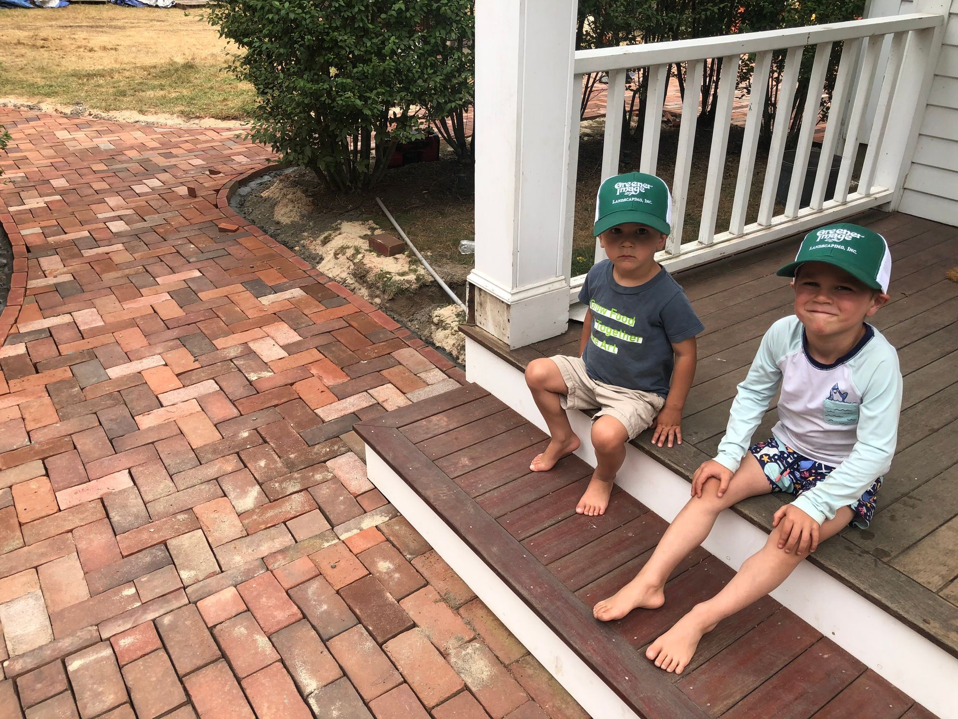 Two young boys are sitting on the steps of a porch.