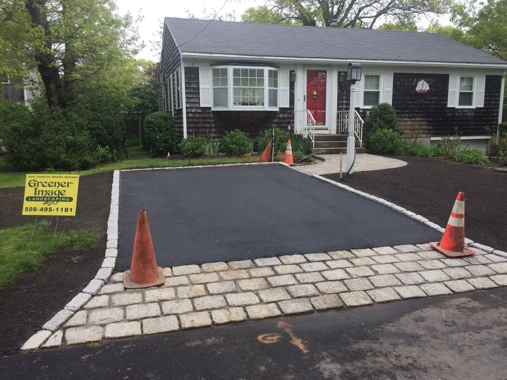 A house with a brick driveway and a sign that says