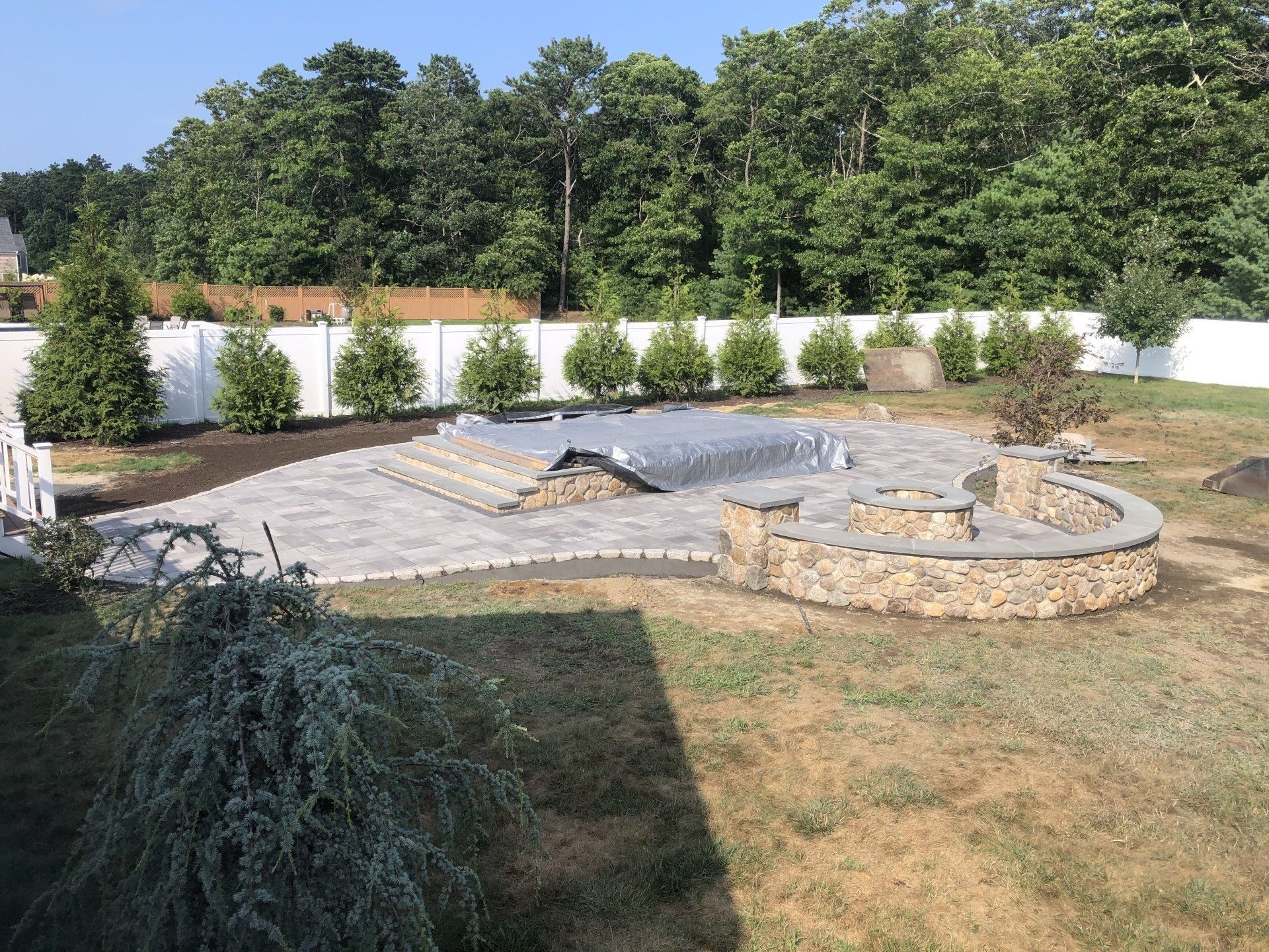 A large backyard with a swimming pool and a fire pit.