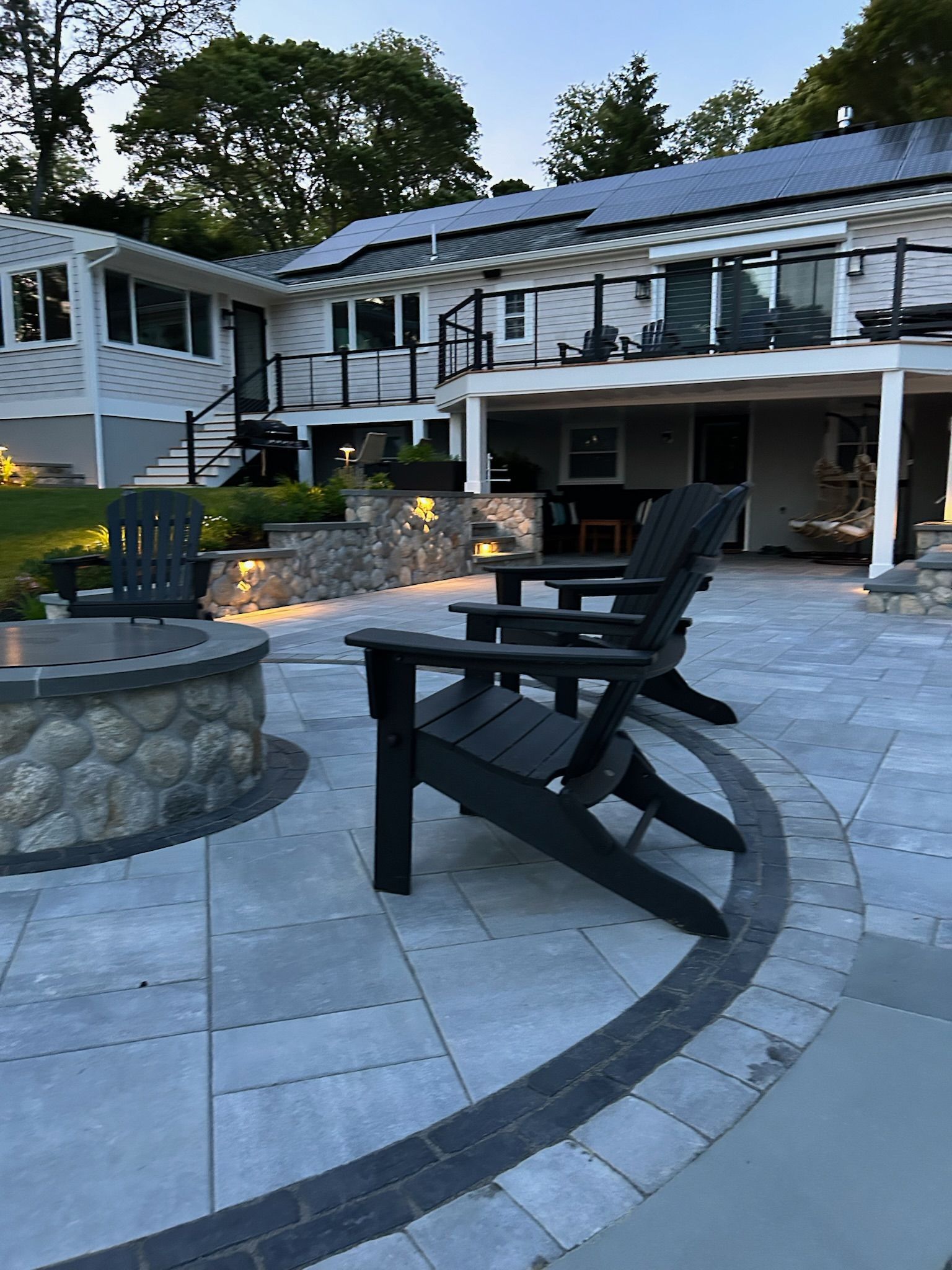 A patio with chairs and a fire pit in front of a house