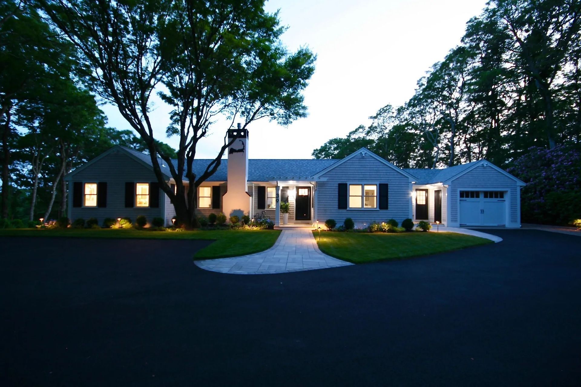 A white house with black shutters is lit up at night
