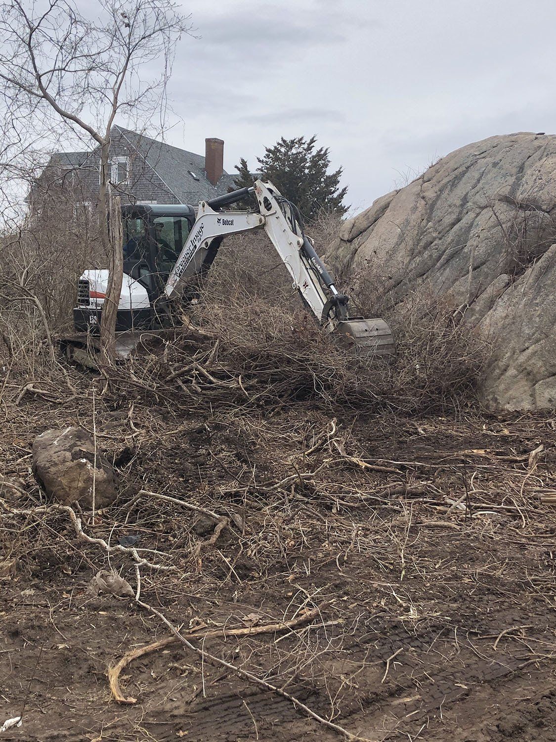 A bulldozer is moving a pile of rocks in a dirt field