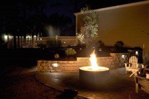 A fire pit is lit up at night in a backyard