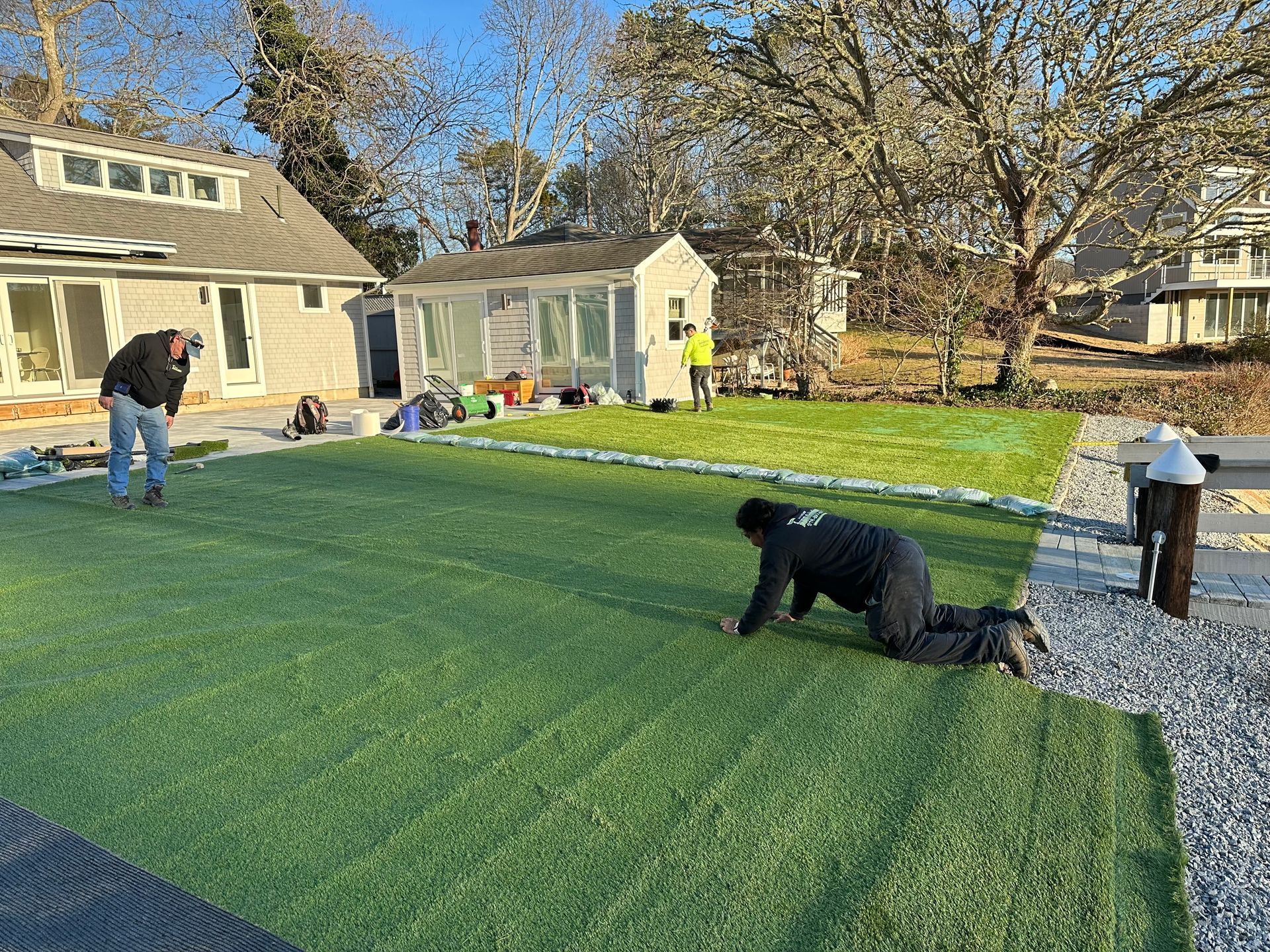 a man is kneeling on a lush green turf lawn in front of a house